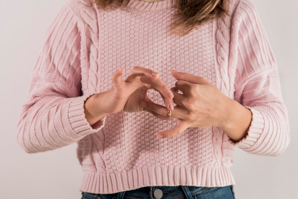 Woman removing a wedding ring from her finger.